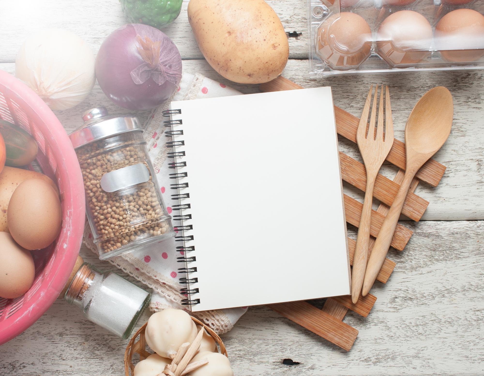 Mesa con cuadernos y recetas sobre fondo cálido